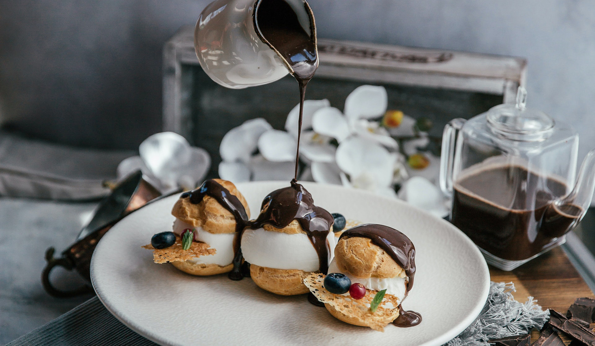 Person pouring chocolate to profiteroles. Photo by Kubra Dogu: https://www.pexels.com/photo/person-pouring-coffee-on-white-ceramic-mug-8774282/